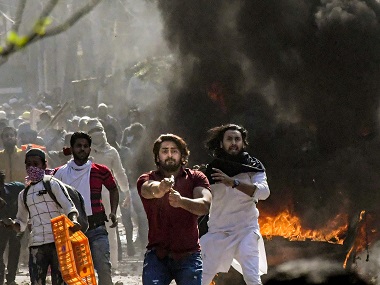 A man with gun charging at policeman during Delhi clashes.